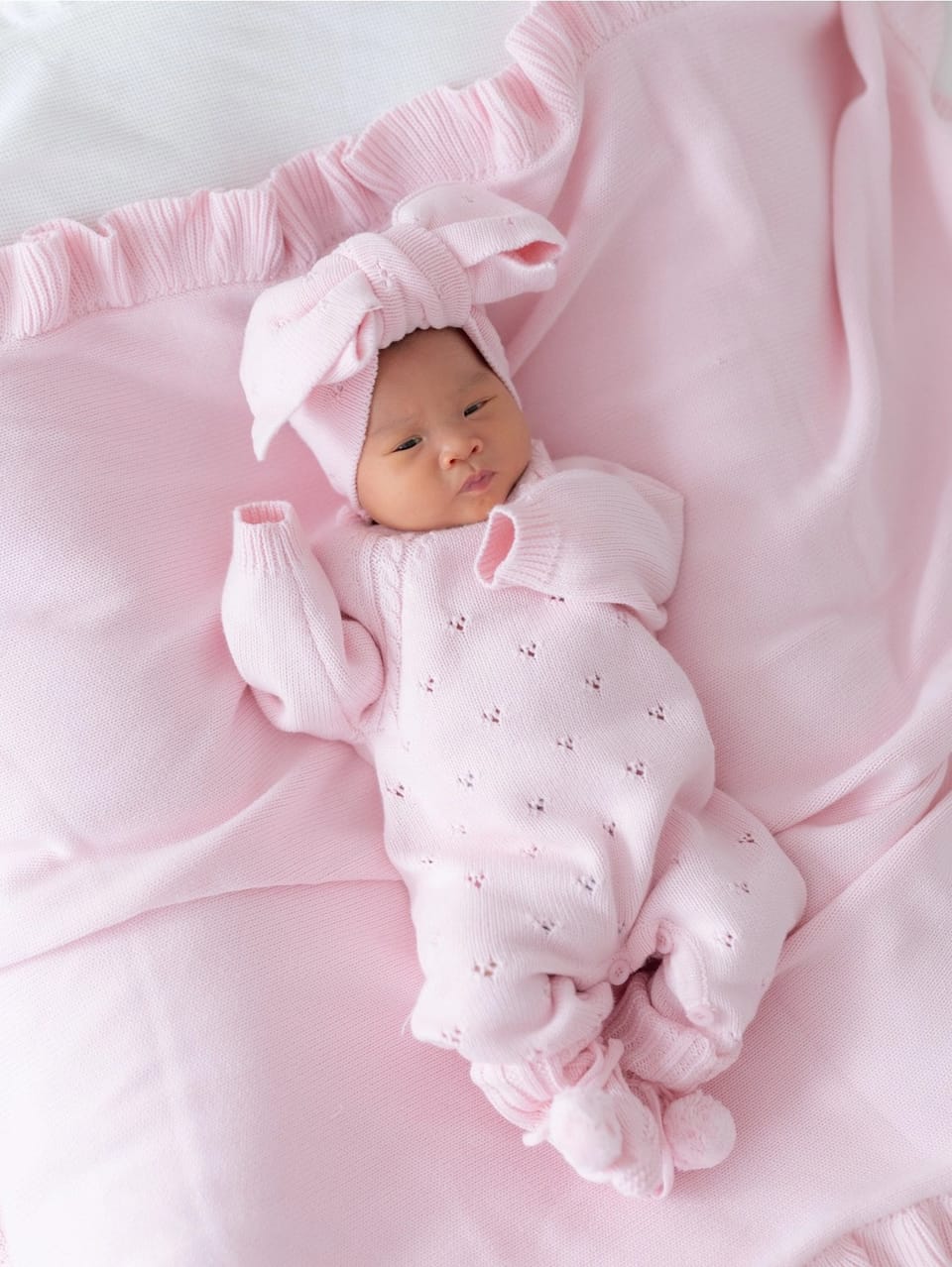 Bebé recién nacida vestida con un conjunto de punto rosa